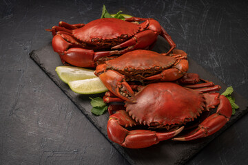 Steamed Red Crab with butter and lemon, Boiled Serrated mud crab on black plate on black background,