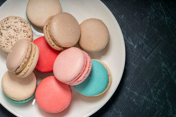 Colorful macarons in white plate on wooden table, Sweet makaron from almond flour and cream.