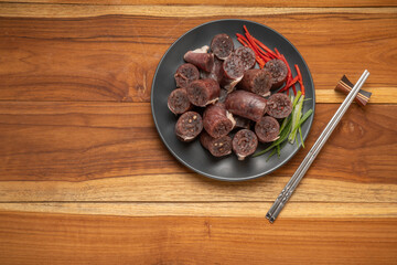 Blood sausage or Sundae in black plate on wooden table background.