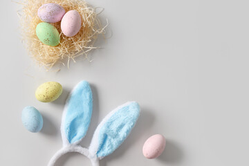 Easter bunny ears, nest and pastel colorful eggs on gray background. View from above. Flat lay. Happy spring greeting card with copy space.