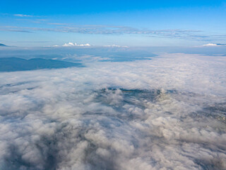 Obraz premium High flight above the clouds in the mountains. Aerial drone view.