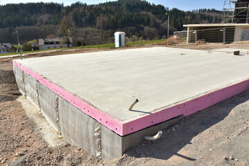 Frisch betonierte Bodenplatte für ein frei stehendes Haus in einem Neubaugebiet