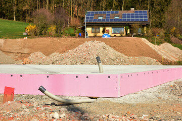 Frisch betonierte Bodenplatte mit Anschlüssen für ein frei stehendes Haus in einem Neubaugebiet