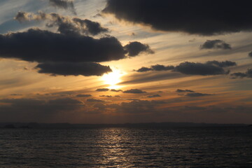 Fototapeta na wymiar 雲の合間から海に沈みゆく夕日