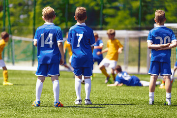 Obraz premium Friends on a Soccer Team Standing United in a Line. Boys in School Sports Team. Teamwork in Youth Sports Team. Children in Soccer Jersey Uniforms and Turf Cleats