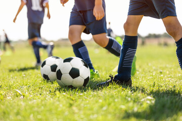 Fototapeta premium Young School Footballers Dribbling Around Cones in Drill on a Sunny Day. Soccer Training Summer Camp for Youth. European Football Training Unit