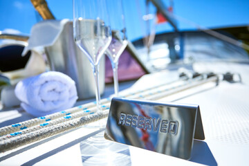 Romantic luxury evening on cruise yacht with champagne setting. Empty glasses and bottle with champagne and tropical sunset with sea background