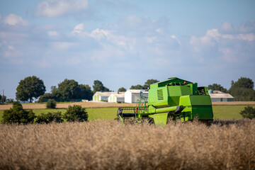 Obraz premium Moissonneuse au travail dans les champs, paysage et agriculture en France.