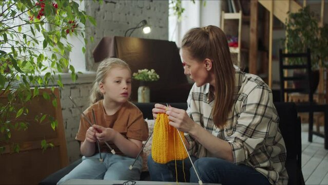 A child chats with his mother about life while she is doing needlework