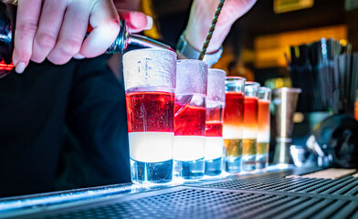 woman bartender hand making collection of colorful shots. Set of cocktails at the bar counter