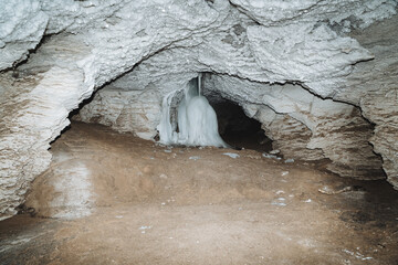 Cave Karlamanskaya Russia Bashkortostan Southern Urals, Karst Hall of the cave is illuminated by the light of a lantern, ice flows down the wall, speleology