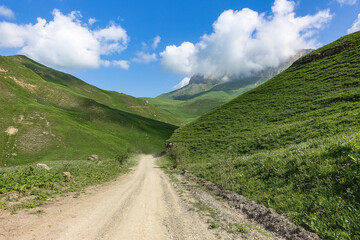 The landscape of the green Aktoprak pass in the Caucasus, the road and the mountains under gray clouds. Kabardino-Balkaria, Russia