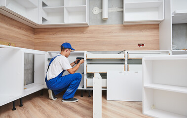 kitchen installation. Worker assembling furniture - 496108987