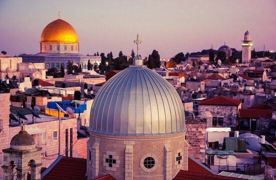 A view on rooftops of Old City of Jerusalem at sunset. Grey dome of Church of Our Lady of the Spasm (Armenian church) and golden Dome of the Rock. Jerusalem , Israel
