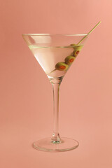 martini glass with olives on pink background
