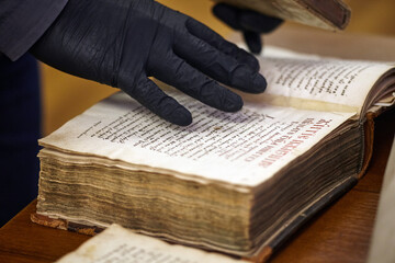 Librarian in gloves holds a rare book.