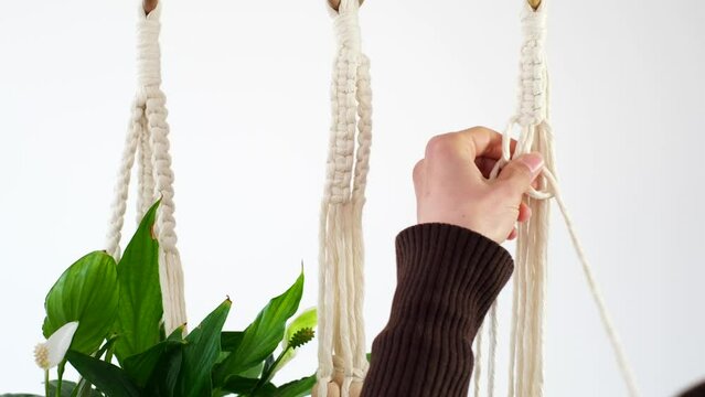 Women's hands weave a flower pot holders in macrame Boho style ties knots cotton threads to create lace