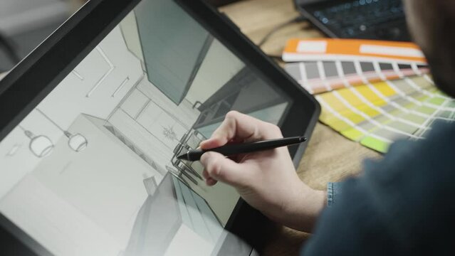 A professional illustrator designer is working on the interior of a modern kitchen. A man creates a digital image using an interactive graphics tablet