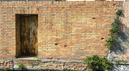 Detail of an old brick wall with a door. Space for your text. Urban rustic background.