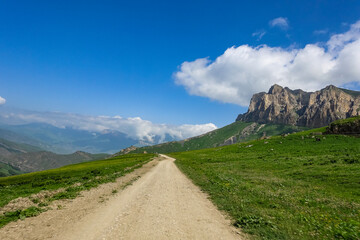 The landscape of the green Aktoprak pass in the Caucasus, the road and the mountains under gray clouds. Kabardino-Balkaria, Russia