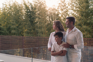 Happy family resting on the balcony of a luxury house surrounded by forest nature. Selective focus 
