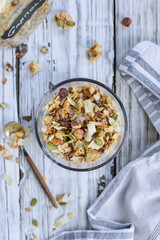 Messy bowl of vegan keto Granola made with pecans, hazelnuts, unsweetened coconut, sunflower seeds, pepita seeds and sweetened with erythritol. Served with low carb almond milk. Top view or flatlay.