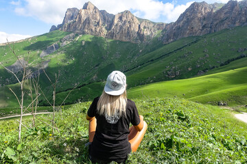Fototapeta na wymiar A girl on the background of a green landscape of the Aktoprak pass in the Caucasus. Russia June 2021.