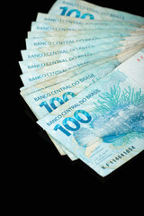 Fototapeta premium Brazilian money. One hundred reais banknotes with black background. finance concept