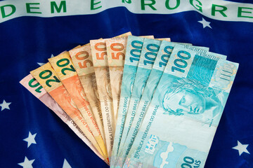 Brazilian money banknotes with Brazilian flag in the background
