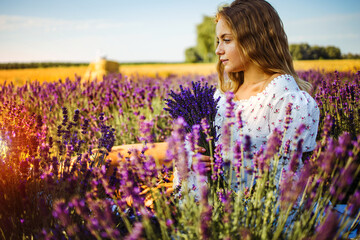 Beautiful girl on the lavender field. Beautiful blonde woman in the lavender field on sunset. Soft focus