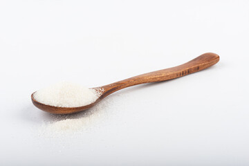 Wooden spoon with white sugar on a white background.