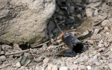 Bottle broken glass between stones rubbish