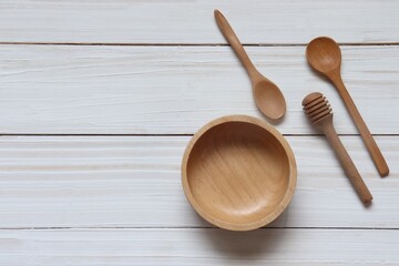 Empty wooden bowl and spoon on white wooden background