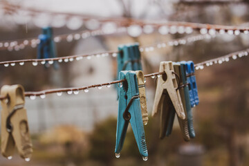 Clothes pins on wire. Rope with pins and raindrops. Laundry concept. Rainy day in village. Rural still life. Water drops and pins close up. Countryside landscape. Spring weather concept. 