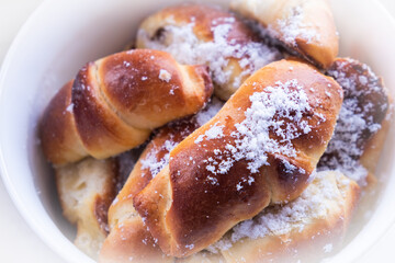 sweet buns with powdered sugar plate close-up