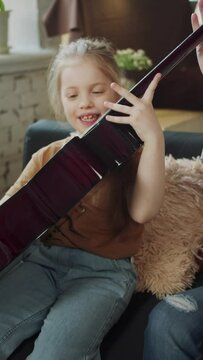 The girl picks up the guitar for the first time and tries to play