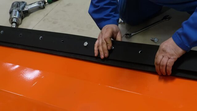 The worker's hands insert the bolt into the gasket of the atv plow system