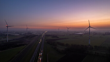 Fototapeta na wymiar Aerial view sunrise of meadows and electric windmills across high speed highway on the morning under a colorful sky natural landscape over the panorama landscape. High quality photo