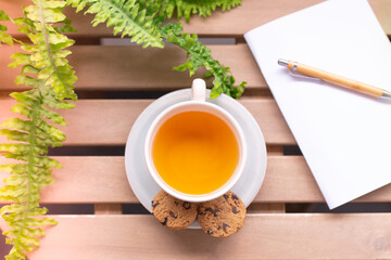 Tea cup placed on an old wooden table with green leaves background with soft sunlight in the morning, giving a fresh feeling Relaxing and calm.