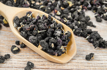 Black wolfberries or black goji berries, in a wooden spoon.