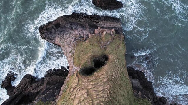 AERIAL: Top down shot of sea crashing against rocky natural arch, Bluepool Gower, 4k Drone