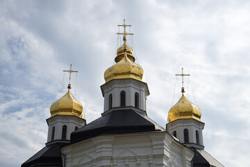 Fototapeta na wymiar Gilded domes of an ancient Orthodox church against the sky. Catherine's Church is a functioning church in Chernihiv, Ukraine.