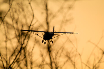 Ein Kleinflugzeug fliegt Richtung Sonnenuntergang. 