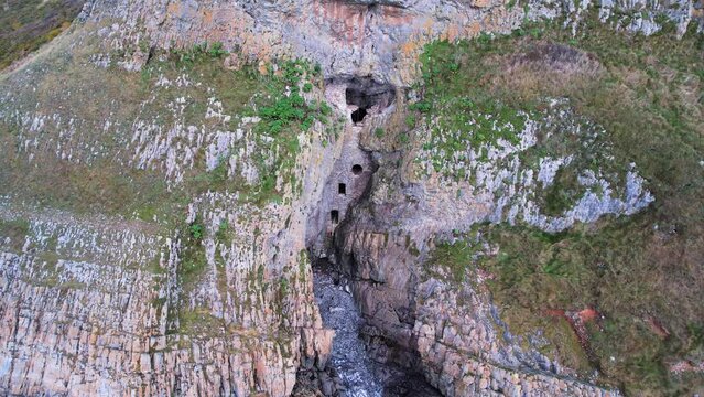 AERIAL: Close circle of man made cave in the side of cliff, Culver Hole, Port Eynon, Gower, 4k Drone