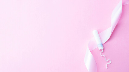 Tampon woman feminine hygiene. Pink ribbon with menstrual tampon on pink background. Menstruation feminine period. Soft tender protection for women critical days.