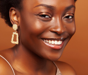 pretty young african american woman with curly hair posing cheerful gesturing on brown background, lifestyle people concept