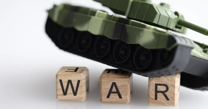 Toy tank stands on cubes with words war closeup