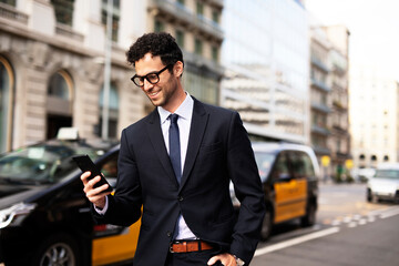 Handsome businessman using the phone. Young elegance man outdoors.