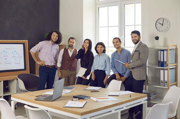 Portrait of happy successful diverse business team gathered in boardroom for brainstorming working together on project posing look at camera. Teamwork representative of smart skilled specialists