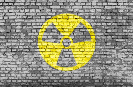 Nuclear danger yellow symbol painted on a brick wall
